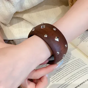 Detailansicht eines braunen Vintage-Armreifs mit silbernen geometrischen Nieten am Handgelenk