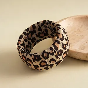 Detaillierte Nahaufnahme eines breiten, stoffumwickelten Armreifs mit klassischem Leopardenmuster