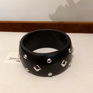 Nahaufnahme eines schwarzen Retro-Armbands mit silbernen Nieten und Rautenmustern
