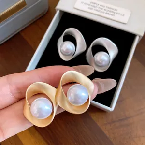 Elegante matgouden geometrische oorknopjes voorzien van een grote witte parel.