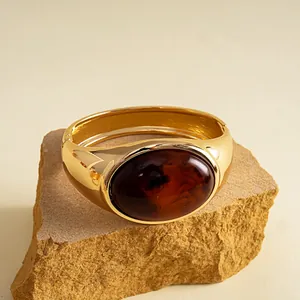 Nahaufnahme eines goldenen Metallarmbands mit großer dunkelbernsteinfarbener ovaler Harzeinlage