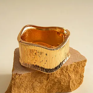 Detailansicht eines goldenen Vintage-Armreifs mit strukturierter Oberfläche auf Fels