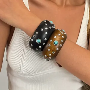 Nahaufnahme von Vintage-Armreifen aus Kunstholz mit Nieten und Türkissteinen am Arm