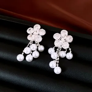 Detailed view of silver-tone floral earrings featuring zirconia and white pearl tassels.