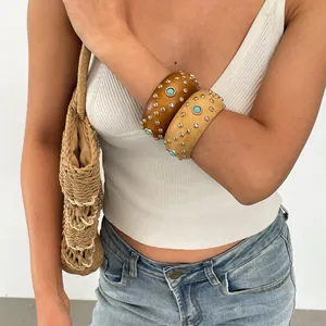 Nahaufnahme von Retro-Armreifen aus Harz mit Goldnieten und Türkissteinen am Handgelenk