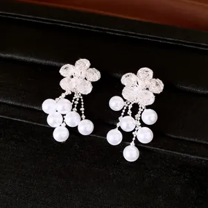 Close-up detail of silver zircon flower earrings featuring elegant hanging white pearl tassels