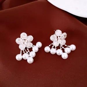 Close-up view of silver zircon flower earrings with elegant dangling white pearl tassels