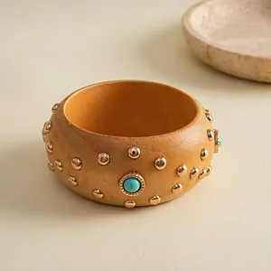 Nahaufnahme eines Vintage-Holzarmreifens mit goldenen Nieten und Türkisstein-Inlays.