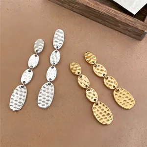 Elegantes pendientes colgantes ovalados de metal martillado en acabados oro y plata