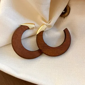 Detailansicht von Retro-Creolen aus dunklem Holz mit goldfarbenen Metallelementen
