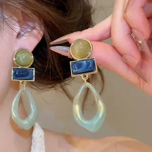 Close-up detail of vintage acrylic geometric drop earrings with marbled blue and green resin