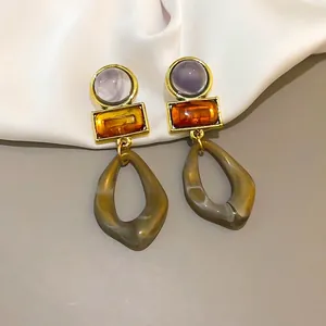 Close-up of vintage acrylic geometric dangle earrings with amber and olive green pendants