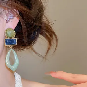 Close-up of vintage geometric acrylic dangle earrings with multi-color design on a model