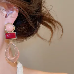 Close-up detail of elegant vintage geometric acrylic pendant earrings in pink and red shades.