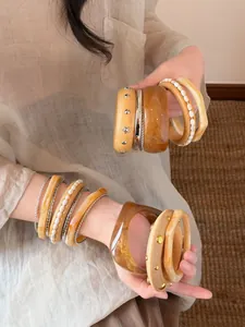 Detailansicht geschichteter unregelmäßiger Harz- und Perlenarmbänder am Handgelenk