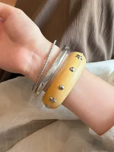 Detailansicht eines Armreif-Sets aus Harz mit Sternbolzen und silbernen Metallarmbändern