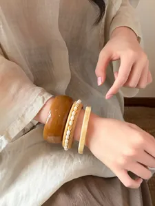 Nahaufnahme von drei unregelmäßigen geometrischen Harzarmbändern an einem Handgelenk