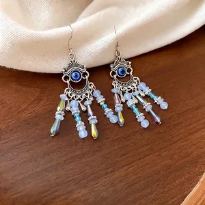 Boucles d'oreilles bohèmes en cristal avec design œil protecteur sur bois rustique