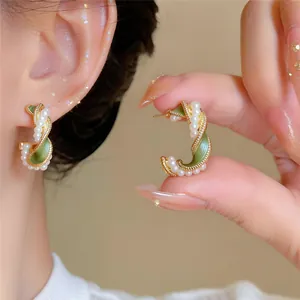 Gedetailleerde opname van vintage groene emaille oorringen met elegante parelaccenten