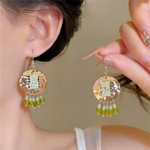 Close-up van stijlvolle ronde retro oorbellen met groene kralenkwastjes op model