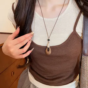 Gros plan d'un collier pendentif goutte avec texture bois acrylique et cordon en cuir