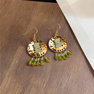 Close-up van vintage gouden oorbellen met groene kralenkwastjes in etnische stijl