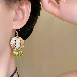 Detailopname van vintage gouden oorbellen met groen-witte kralenkwastjes
