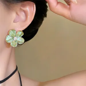 Detailopname van elegante vintage groene gerimpelde bloem oorknopjes aan het oor
