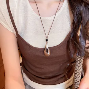 Détail d'un collier pendentif goutte d'eau coréen avec cordon en cuir marron sur modèle