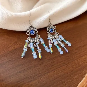 Gros plan de boucles d'oreilles bohèmes à pampilles en cristal avec motif œil bleu.