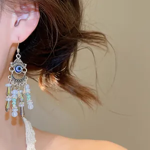 Vue détaillée de boucles d'oreilles bohèmes à pompons en cristal portées sur une oreille