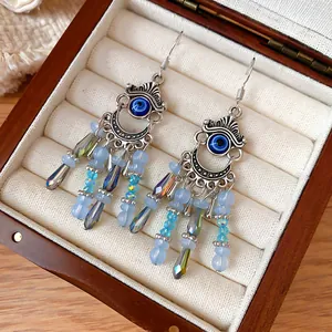 Vue détaillée de boucles d'oreilles bohèmes vintage avec œil bleu et pompons en cristal