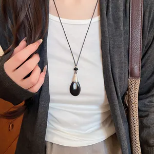 Élégant collier pendentif goutte d'eau noire sur un cordon minimaliste en cuir noir sur modèle