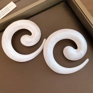 Detail van minimalistische wit parelmoer spiraal oorbellen met gedraaid ontwerp