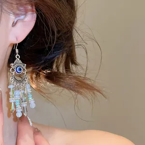 Détail en gros plan de boucles d'oreilles bohèmes à pompon avec motif œil bleu