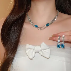 Detail view of sparkling rhinestone necklace and blue oval pendant earrings set