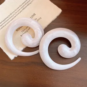 Gedetailleerd overzicht van elegante parelmoeren spiraal oorbellen op een textuur achtergrond