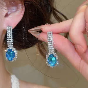 Close-up of elegant blue oval drop earrings featuring sparkling rhinestones for banquet.