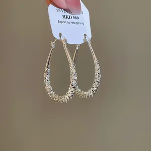 Detailed macro view of silver geometric waterdrop earrings with intricate textured details
