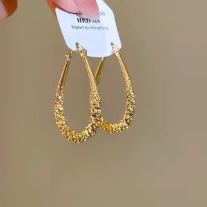 Detailed view of golden geometric teardrop hoop earrings with elegant crinkled texture finish