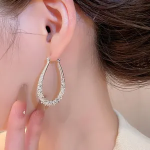 Detailed close-up showing a sparkling silver geometric teardrop hoop earring on ear