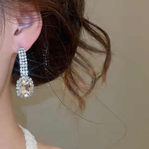 Close-up of elegant oval crystal drop earrings featuring sparkling rhinestone details.