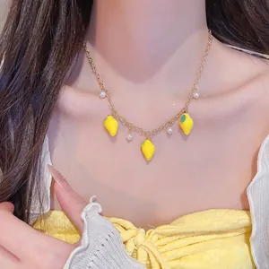 Detailed close-up of a sweet resin lemon and pearl pendant necklace on a delicate gold chain