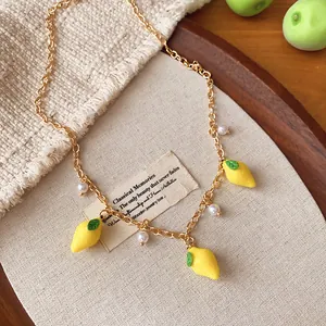 Detailed view of a sweet lemon pendant necklace with pearls on a rustic linen background