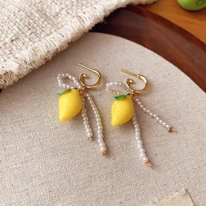 Close-up detail of sweet resin lemon earrings with elegant pearl tassels and gold hoops