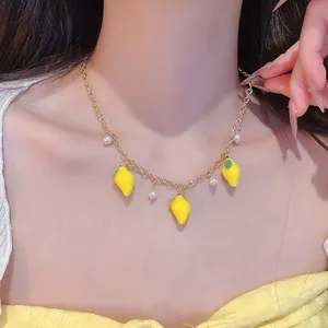Close-up of sweet lemon and pearl pendant necklace worn by a female model.