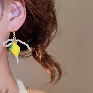 Exquisite resin lemon earring with elegant pearl bow design shown on model's ear