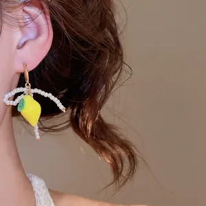 Detail shot of a sweet lemon resin earring with a white pearl bow tassel on a model.
