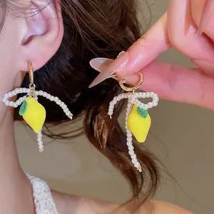 Detailed macro view showing sweet pearl bow earrings with yellow resin lemon charms.