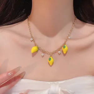 Close-up of sweet gold chain necklace featuring resin lemon charms and elegant white pearls